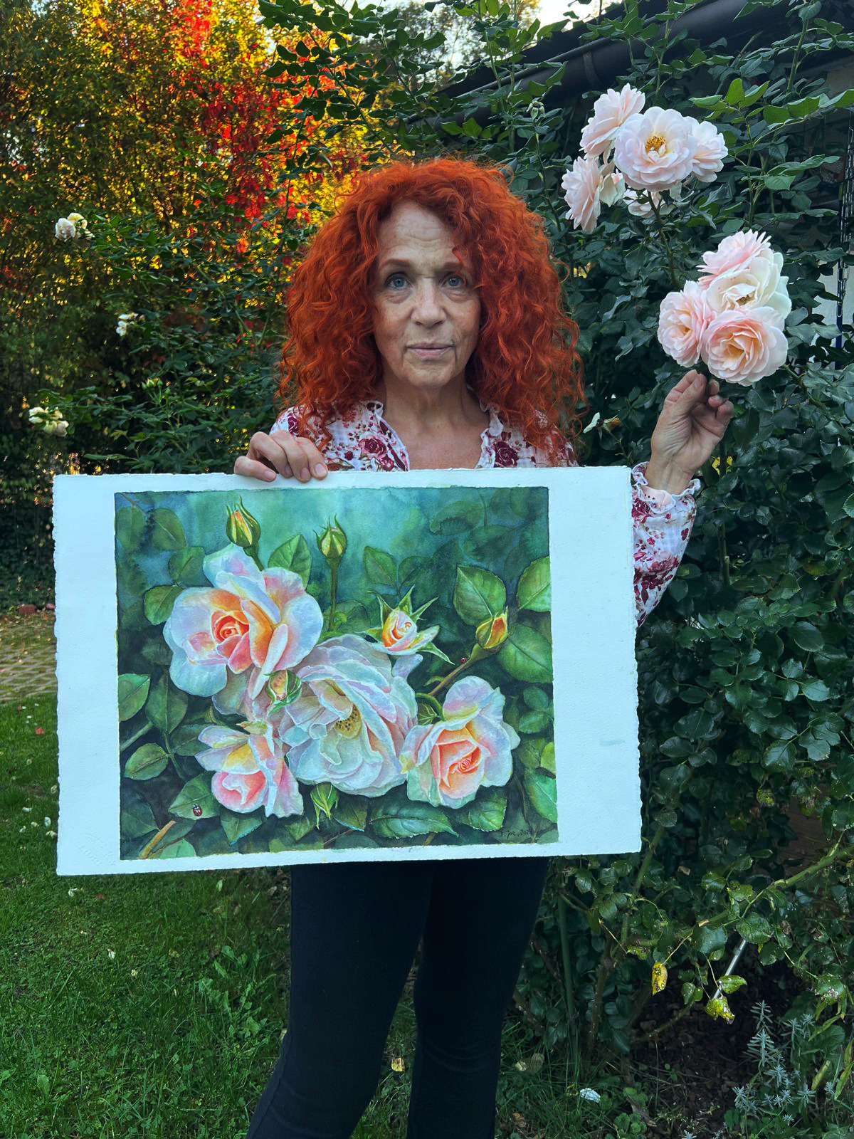 Doris Joa holding her rose watercolor in the garden